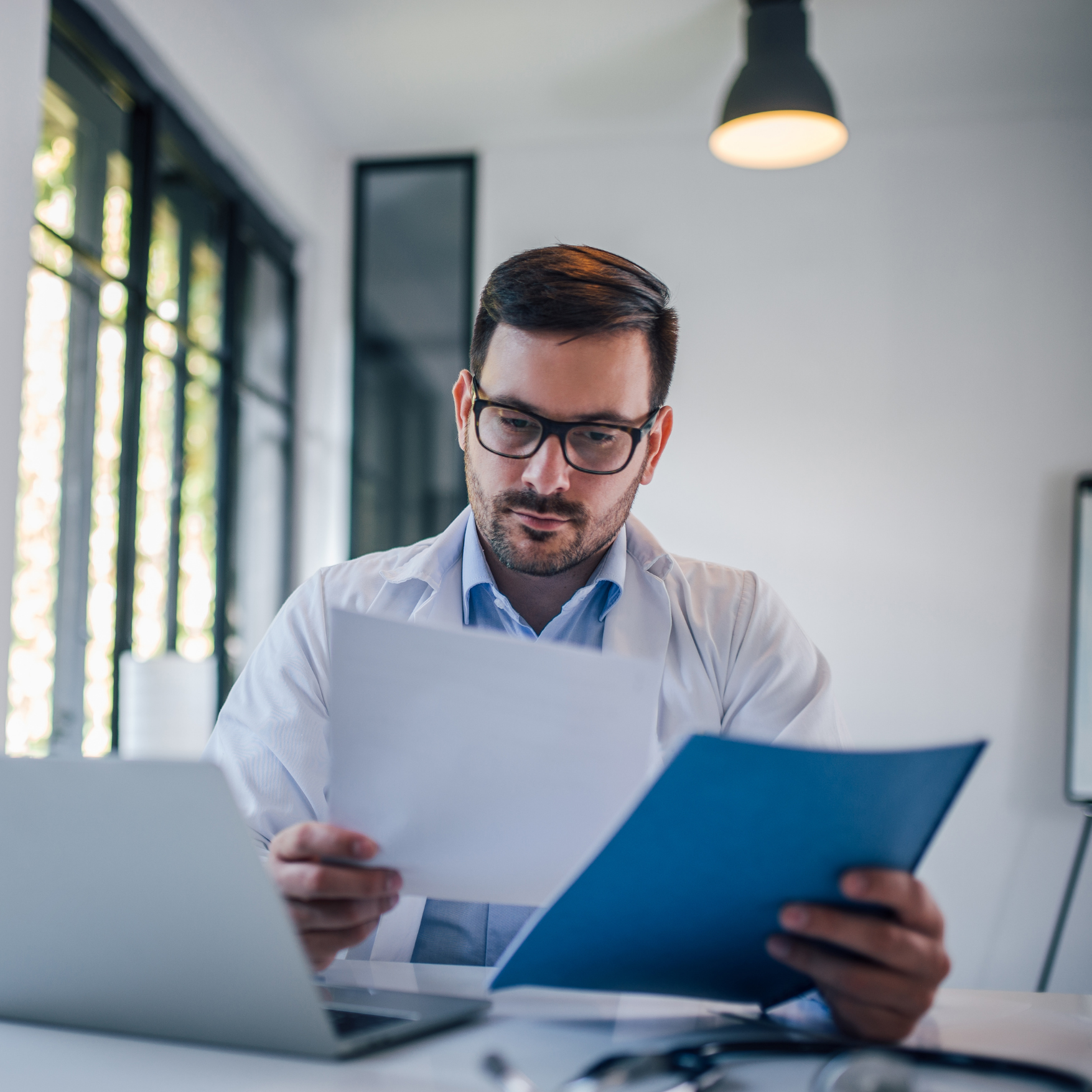 A healthcare accreditation consulting professional reviewing regulatory documents at a desk, focused on ensuring accuracy and adherence to standards in a professional office setting.