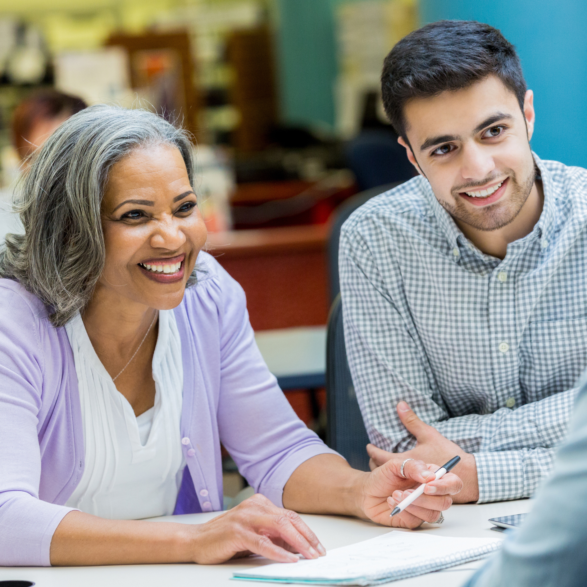 Two colleagues smiling and collaborating at a desk about accreditation consulting and joint commission.