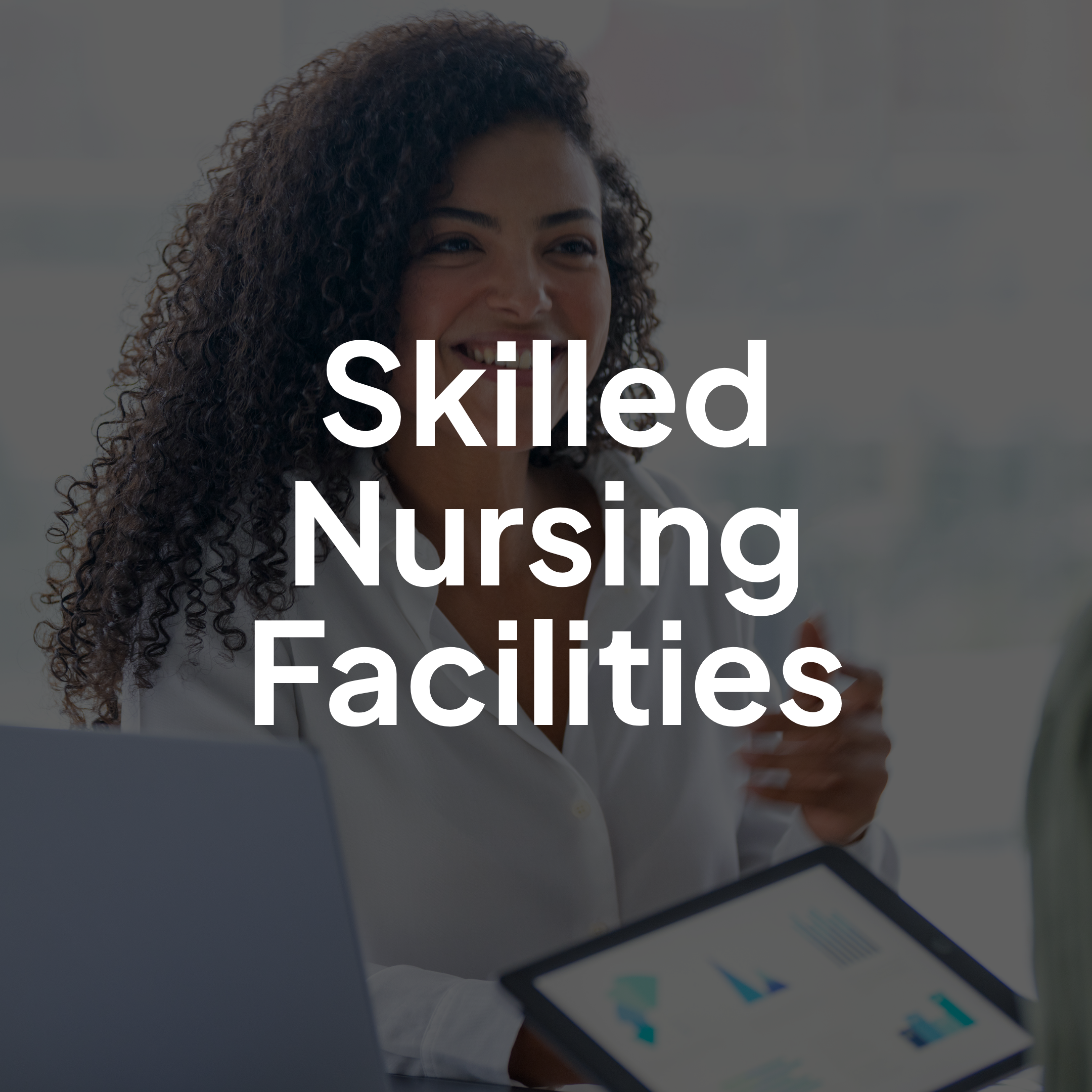 Skilled nursing facility professional reviewing information on a tablet in a senior healthcare office.