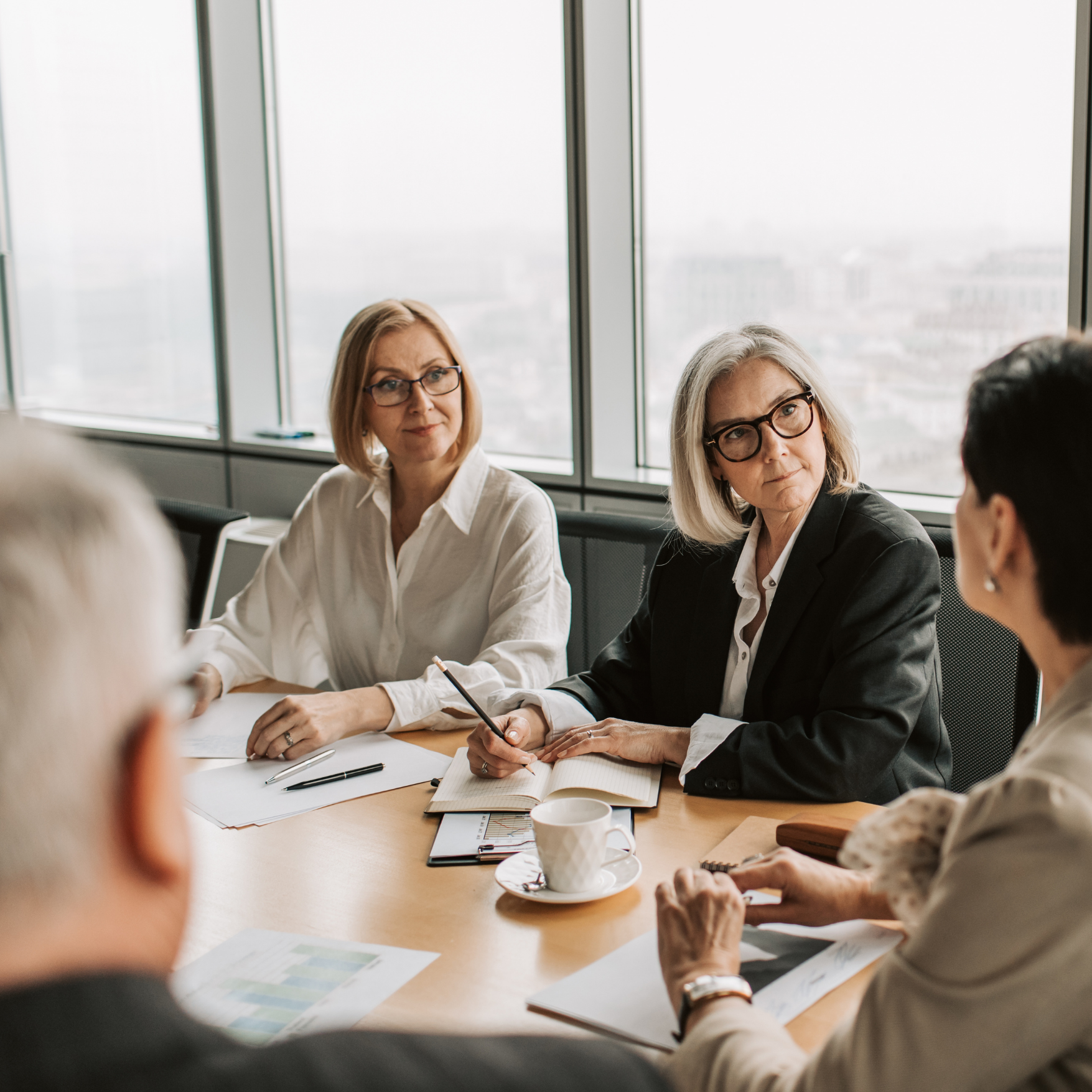 Four long-term care accreditation consulting support professionals seated around a conference table, engaged in a discussion.