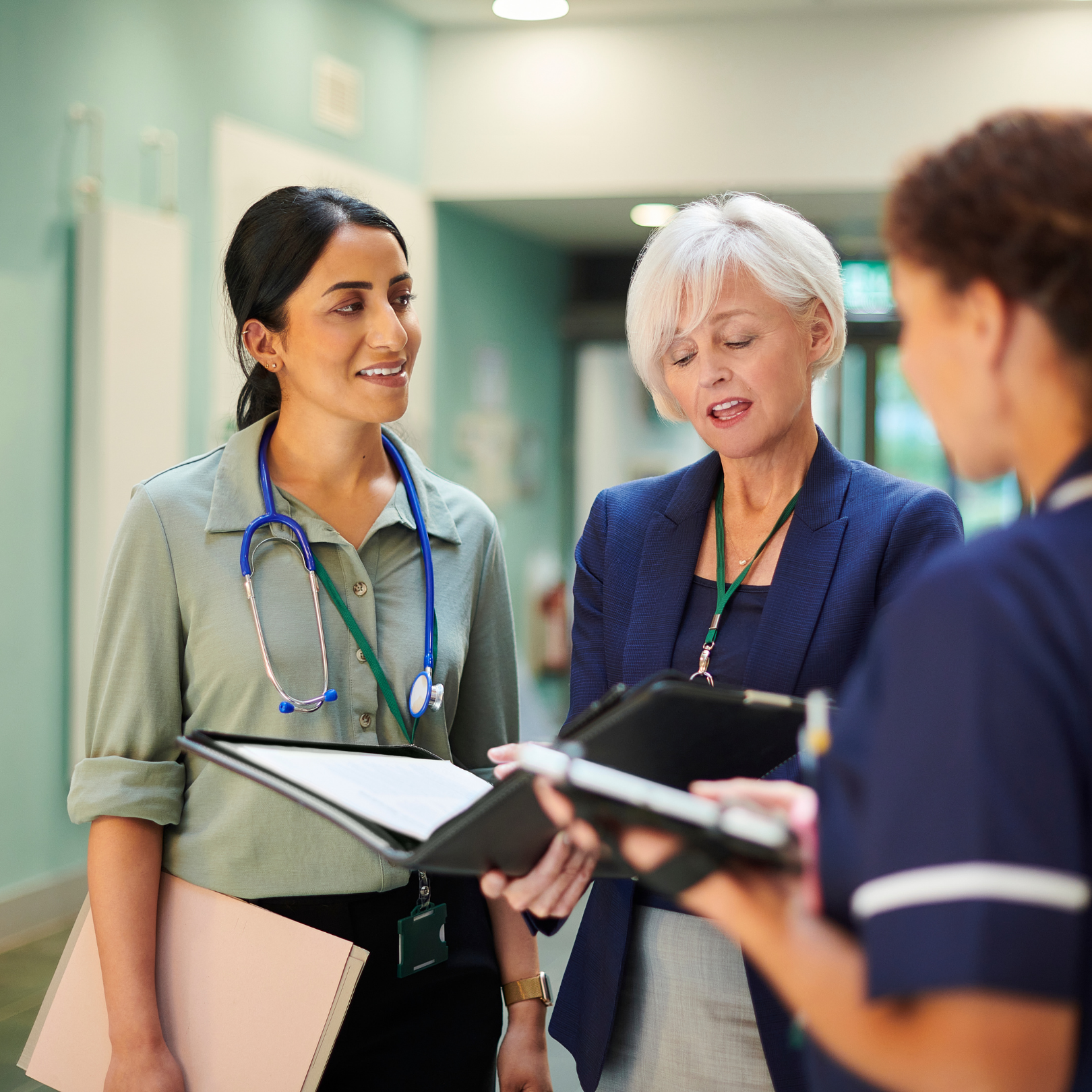 Healthcare professionals reviewing documentation together in a clinical hallway, representing collaborative guidance, oversight, and hands-on accreditation consulting.