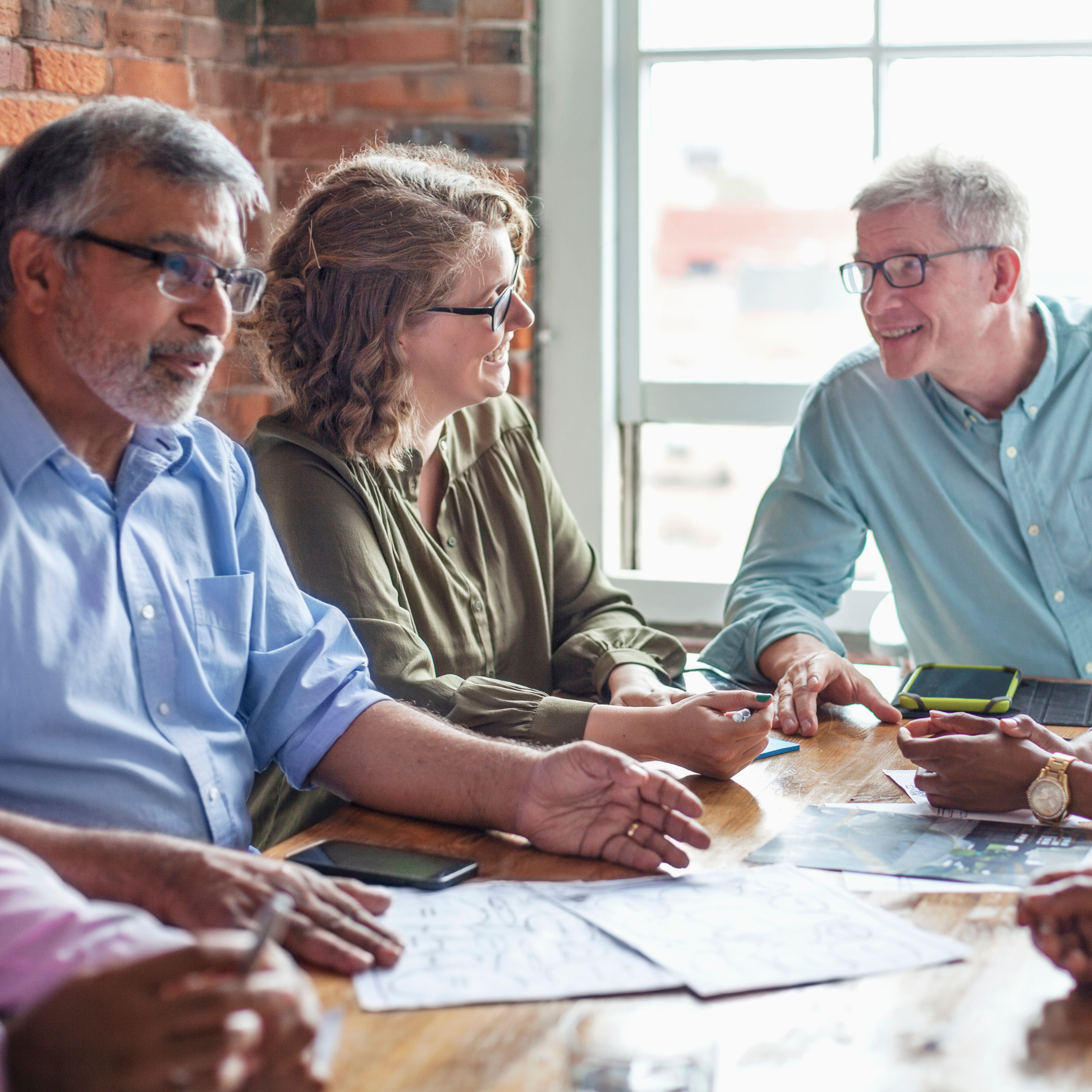 Diverse group of adults seated around a table collaborating and discussing senior living staff training programs.