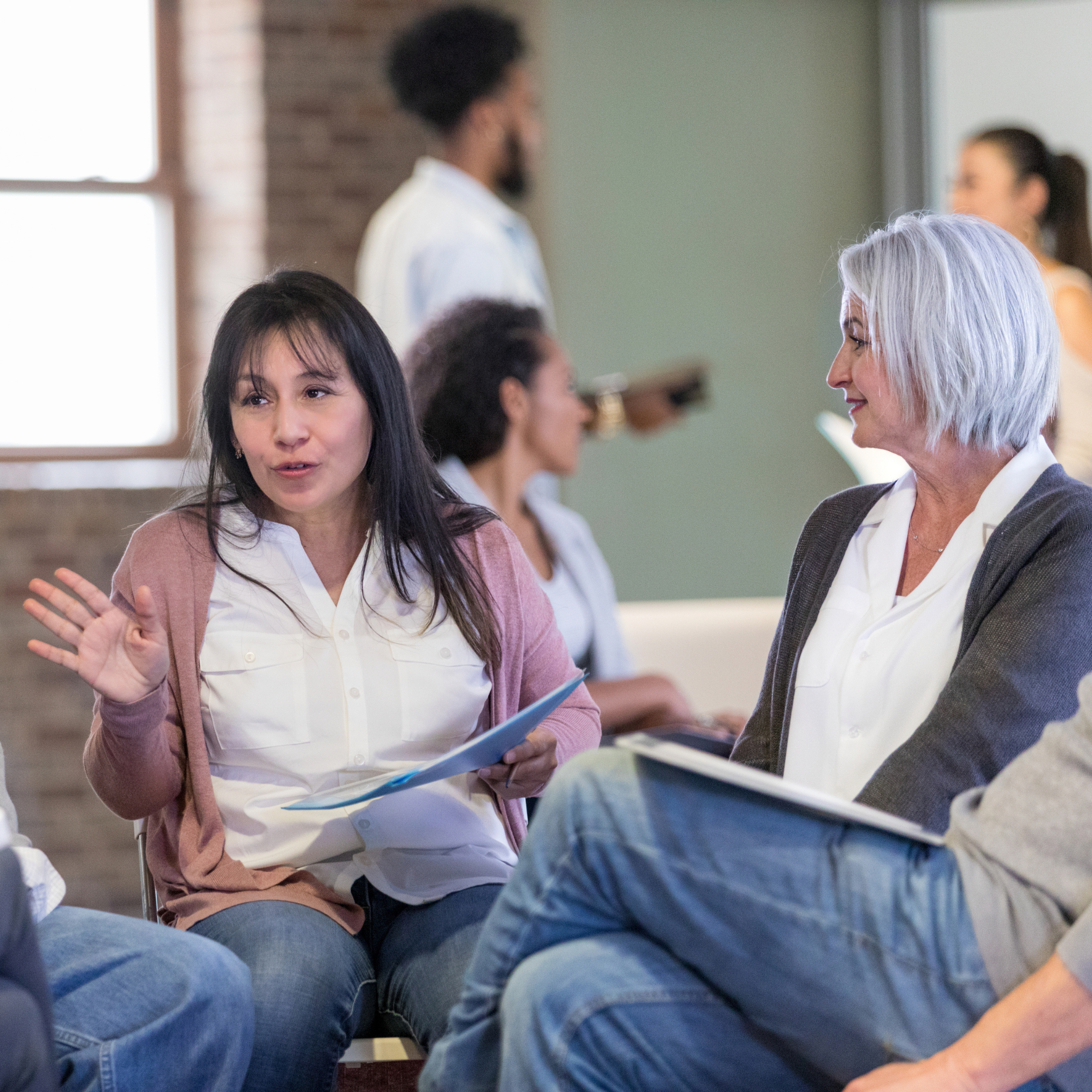 Woman speaking and gesturing during a small group discussion about senior living accreditation.
