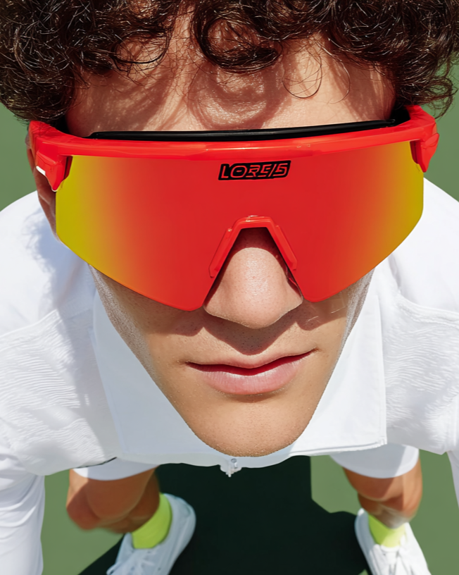 Close-up of a person wearing large, red and yellow sports sunglasses with the brand name 'LORIS' on the lens, outdoors.