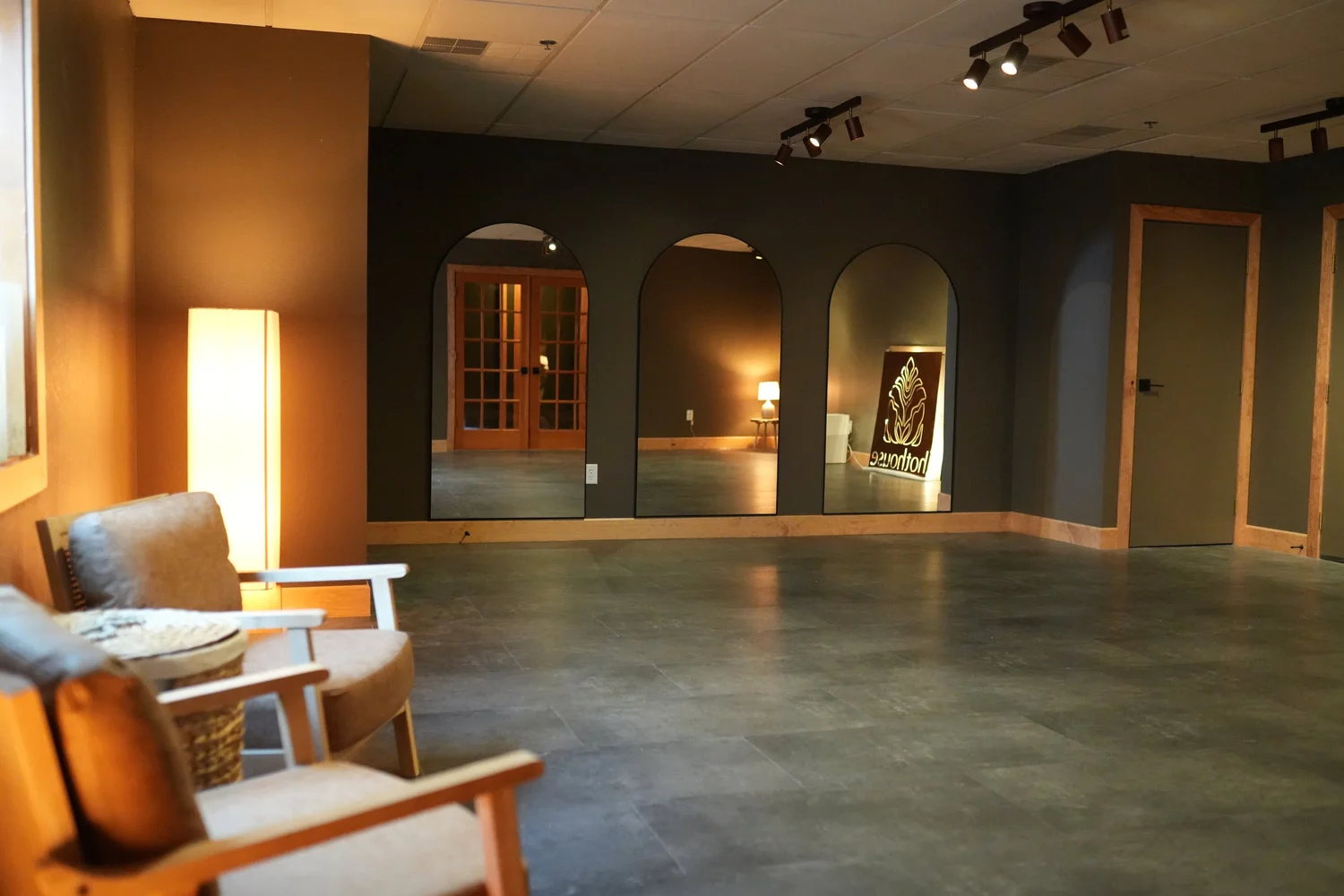 The hothouse community studio room, with mirrored arches, a floor lamp and a lounge chair.