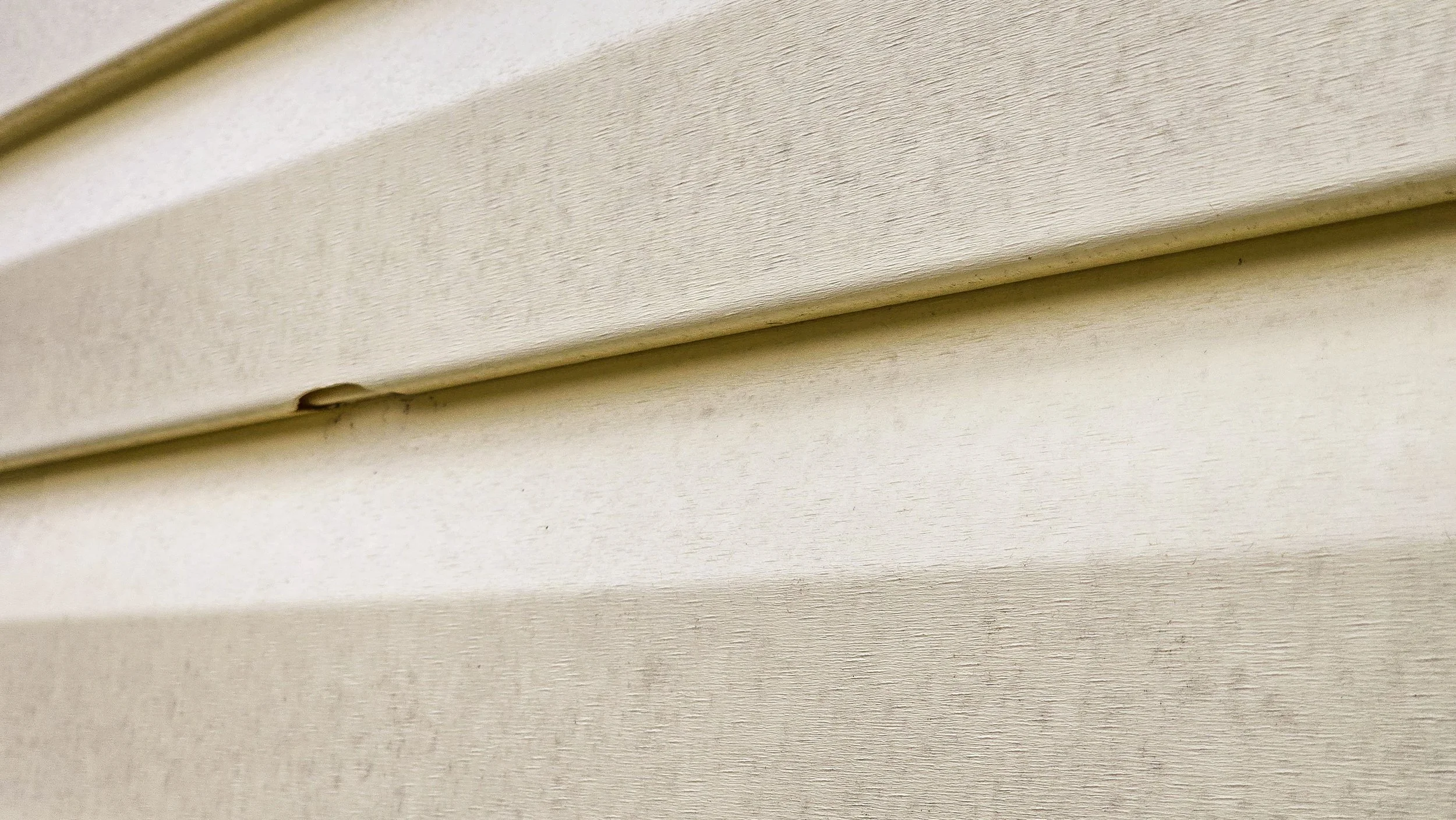 Close-up of beige exterior siding made of horizontal wooden or vinyl planks.