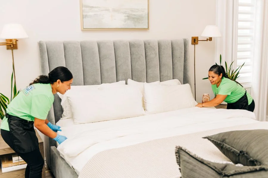 Two Neat and Repeat Cleaning technicians arranging pillows on a made bed