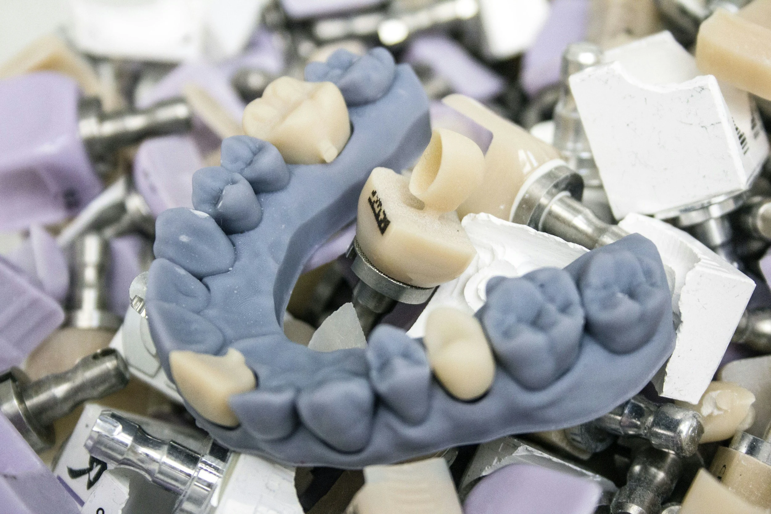 Collection of dental prosthetics and molds, including a gray dental arch with artificial teeth, among other dental tools and materials.