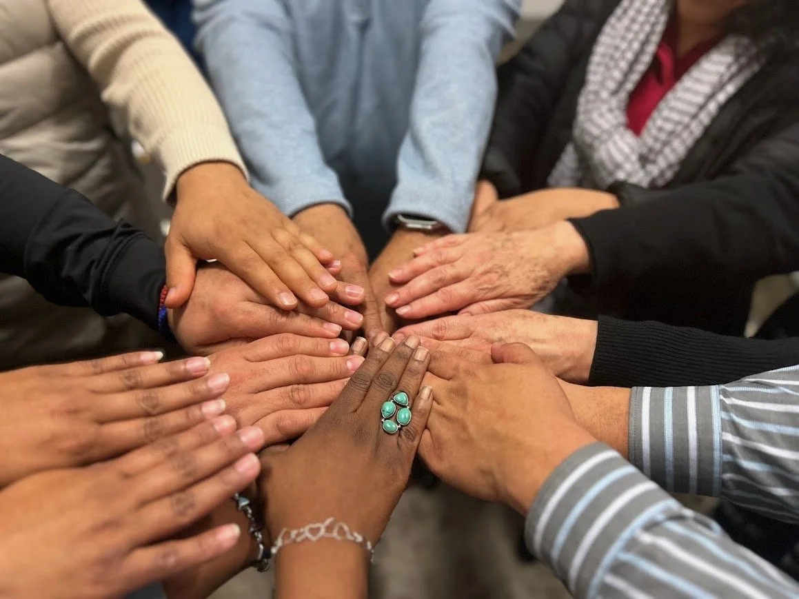 Group of diverse people placing their hands together in a unity gesture.