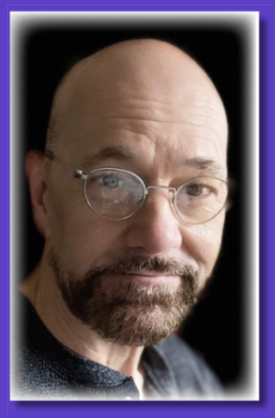 Close-up of freelance copywriter with glasses and a beard looking at the camera.