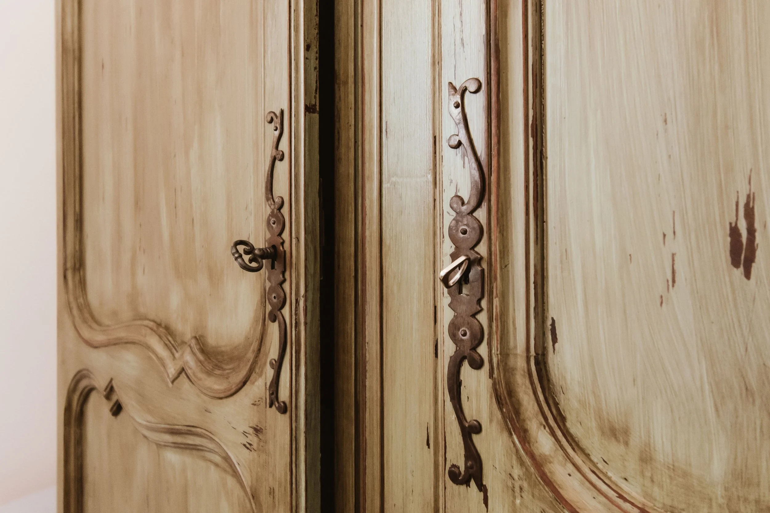 Antique wooden wardrobe with ornate carved details and metal handles.