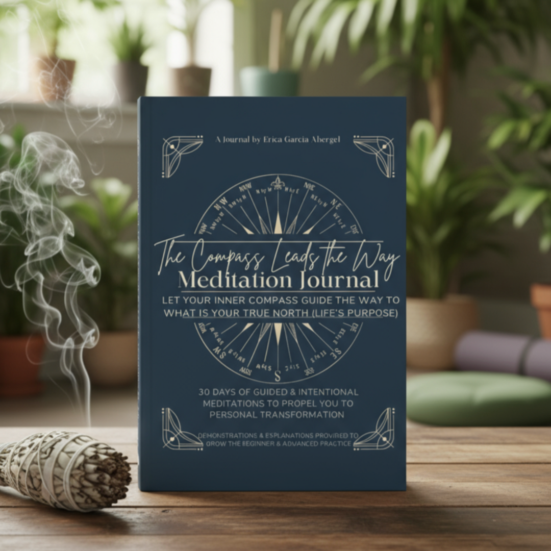 A meditation journal titled 'The Compass Leads the Way Meditation Journal' by Erica Garcia Abergel, featuring a blue cover with a compass design, placed on a wooden table with burning sage and greenery in the background.