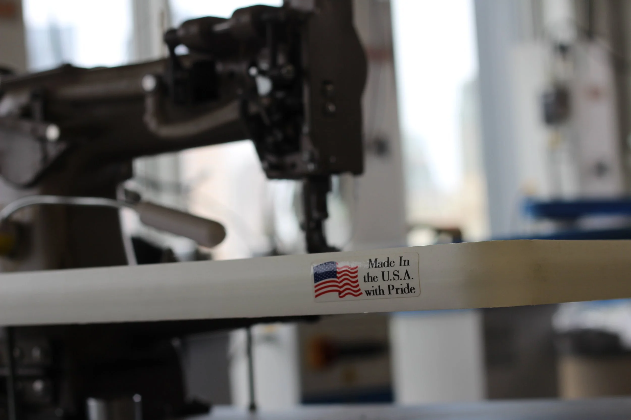 Close-up of a machine with a sticker that reads "Made in the U.S.A. with Pride" and has an American flag, in a factory or workshop environment.
