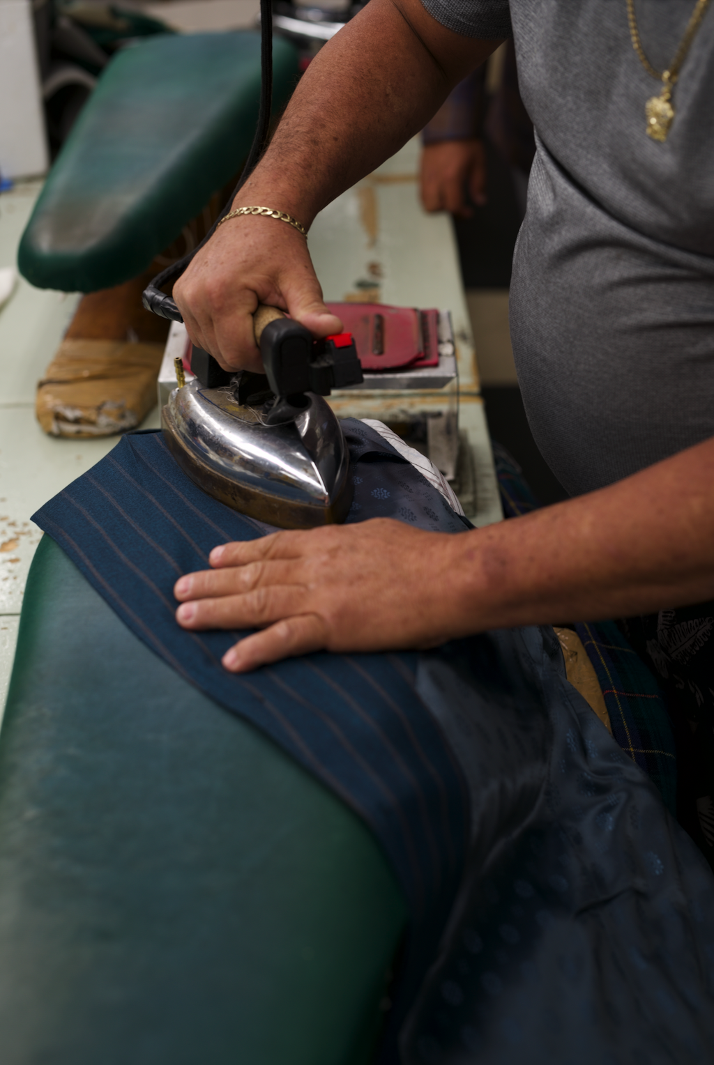 Person ironing a dark striped fabric on an ironing board.
