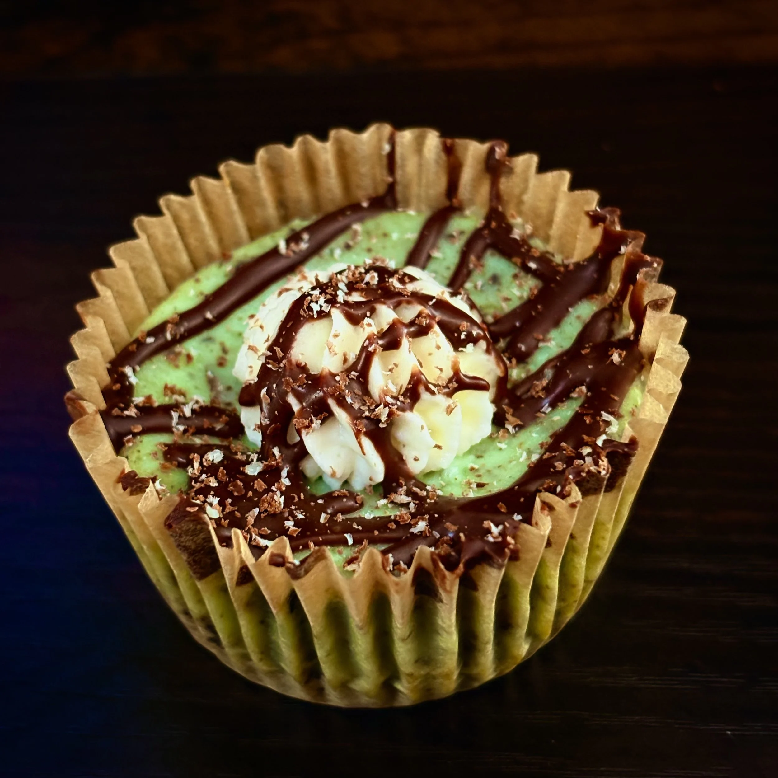Decadent Mint Chocolate Chip Cheesecake slice displaying a layered structure: a mint Oreo crust, a creamy, light green filling loaded with chocolate chips, and a garnish of Andes Mints.