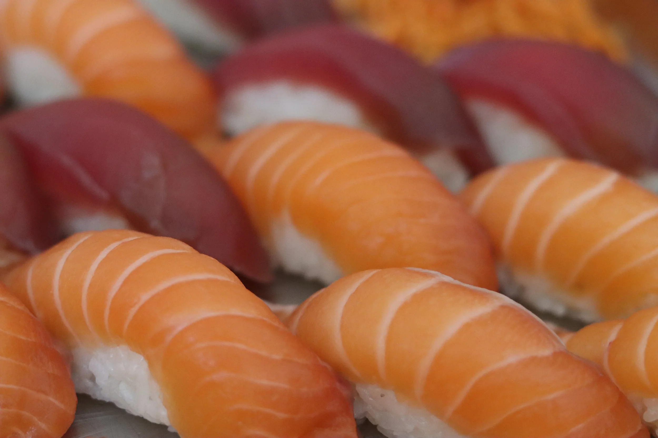 Nahaufnahme von Sushi mit rotem Fisch, Orangenkarotten und weißem Reis.