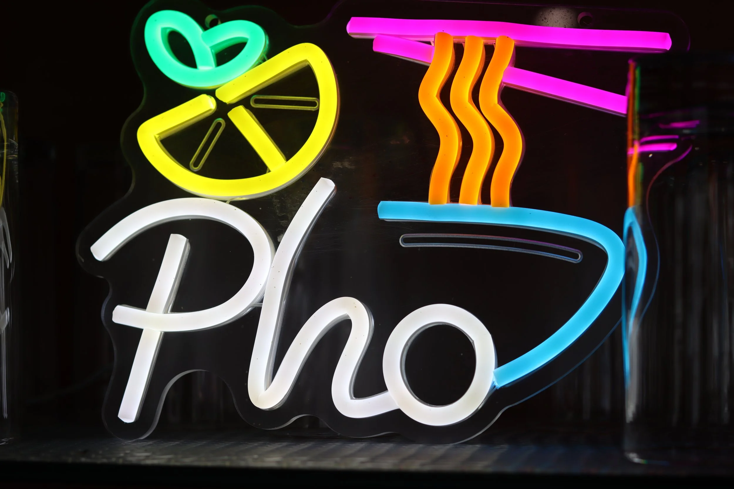 Bunte Neon-Schilder mit verschiedenen Formen und Texten vor einem schwarzen Hintergrund.