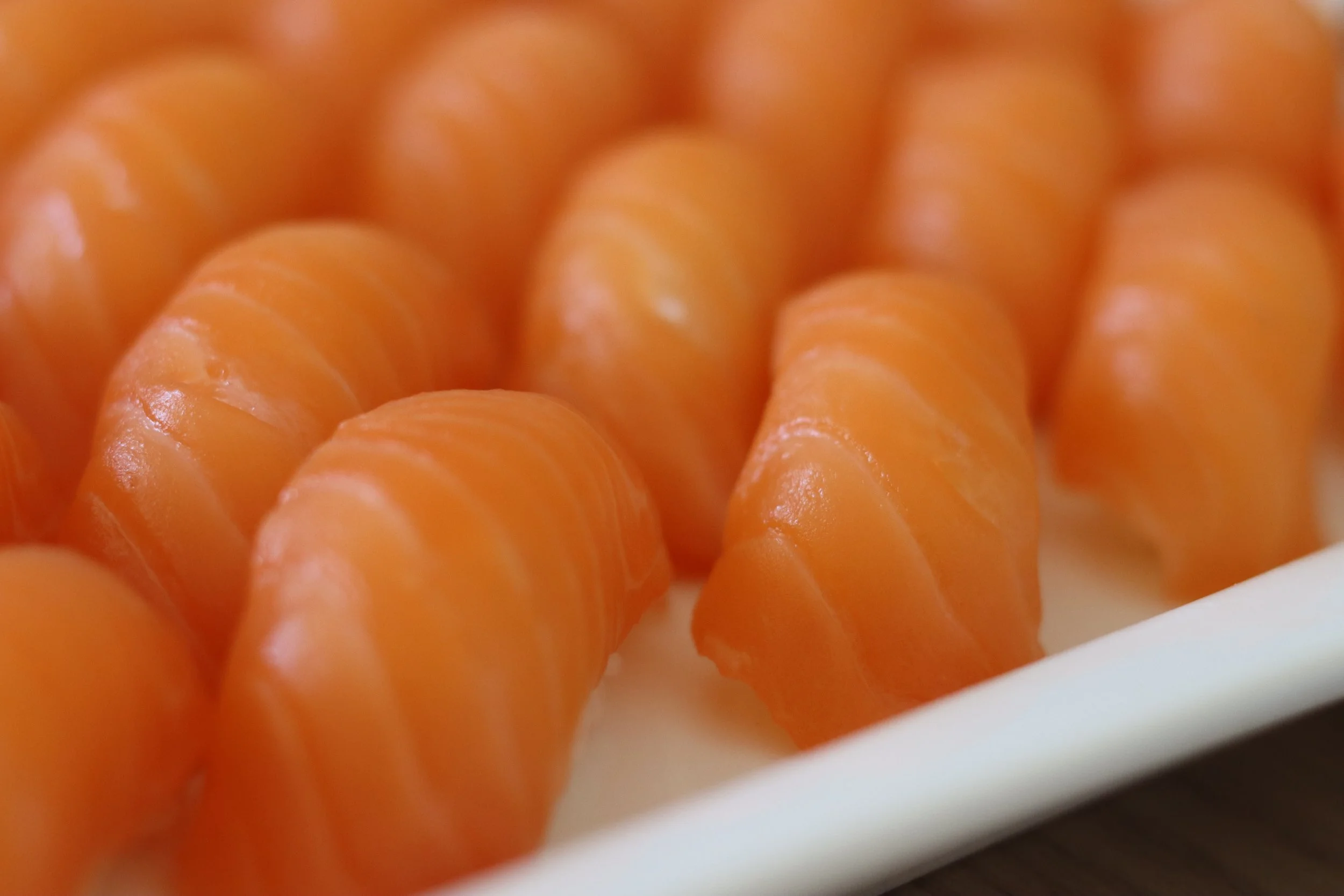 Nahaufnahme von orangefarbenen Jakobsmuscheln auf einem weißen Teller.