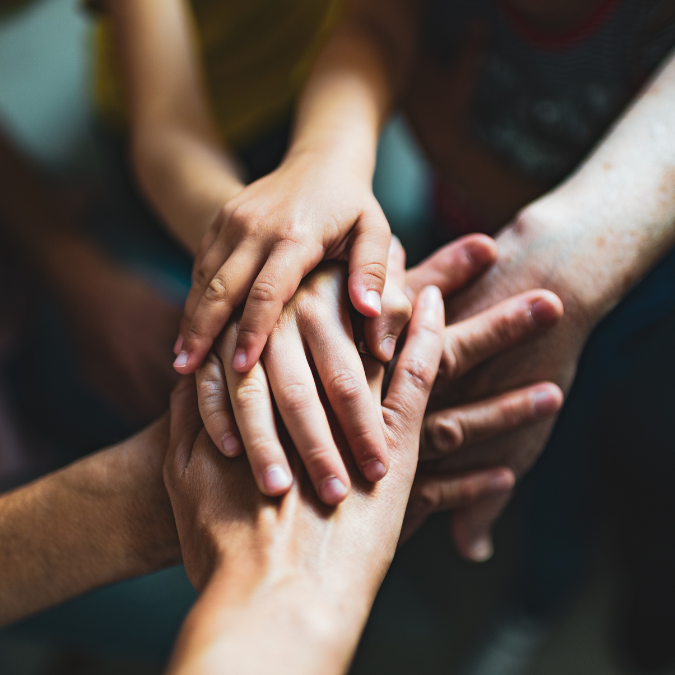 a group of people holding hands in a therapeutic setting.