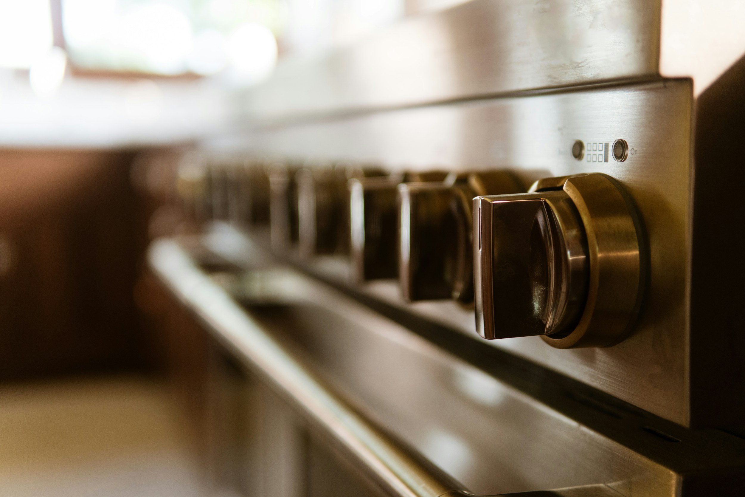 Close-up of a stainless steel stovetop with black control knobs.