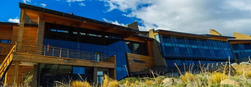 Modern house with wooden and glass exterior under a partly cloudy sky.