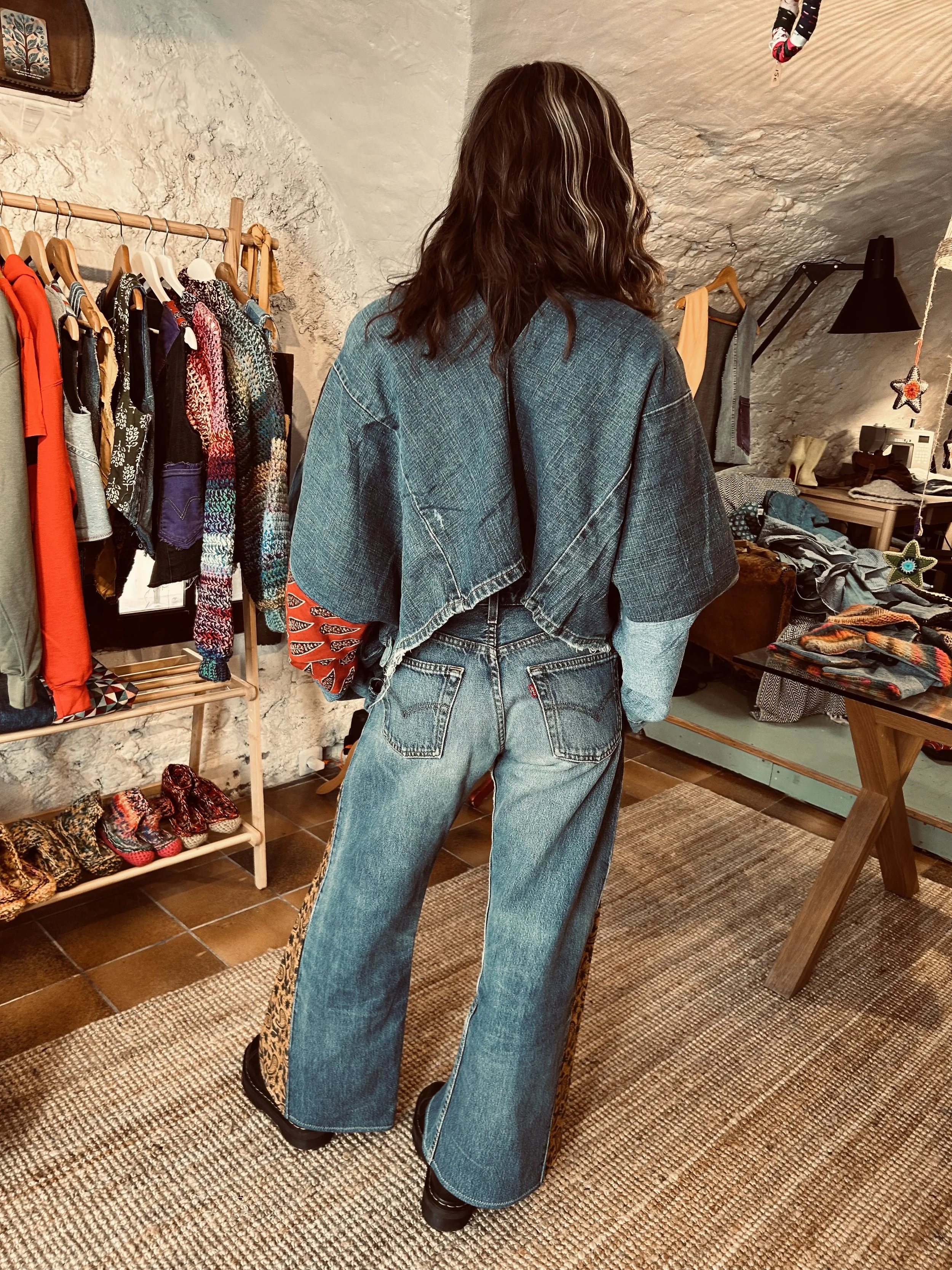 Une femme portant un jean et un vêtement en denim dans une boutique de vêtements vintage.