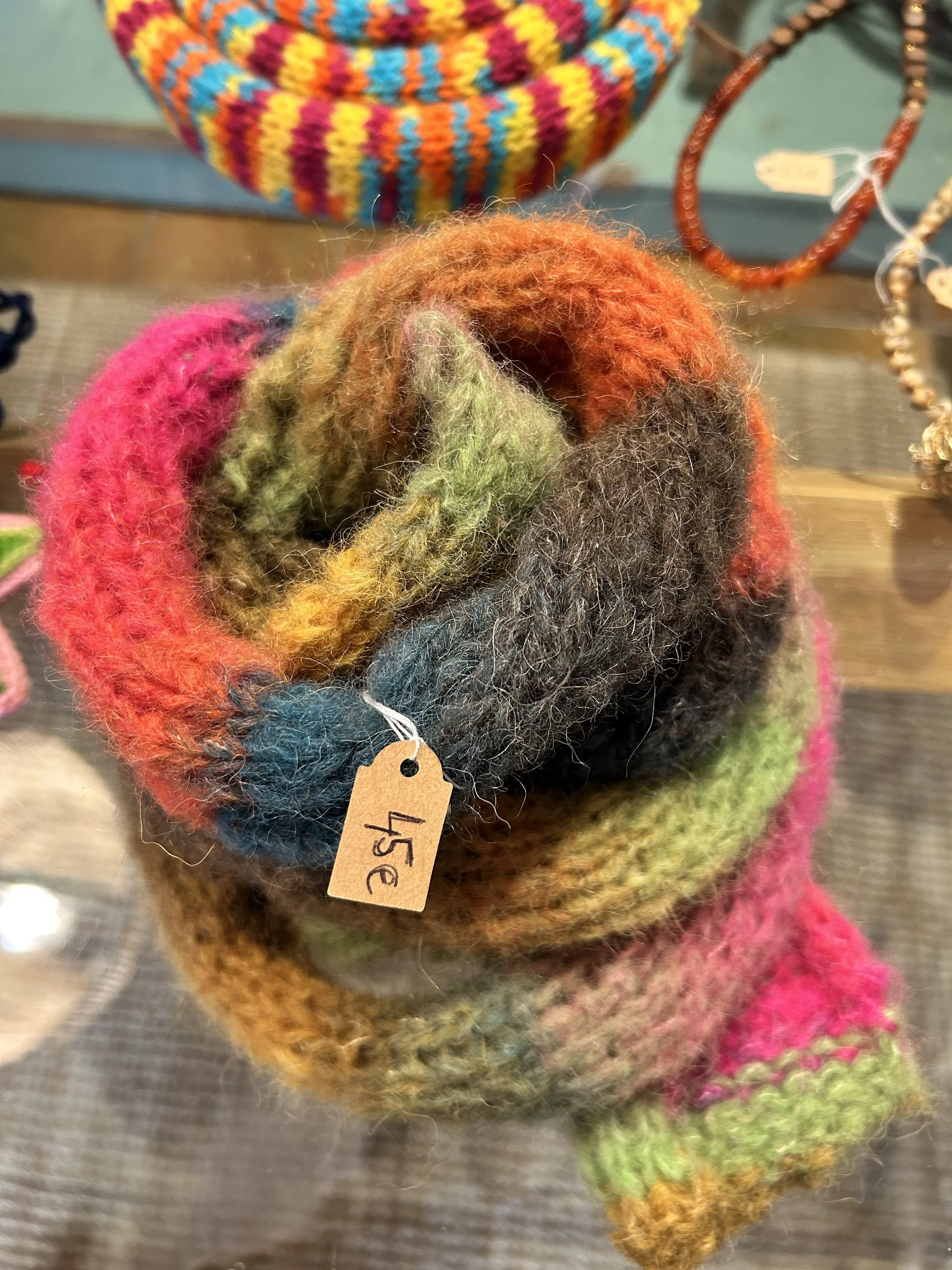 Un écheveau de laine multicolore enroulé, avec une étiquette en papier marquée «5€» attachée.