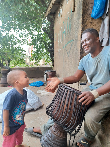 A man sitting outside a building shaking hands with a young boy.