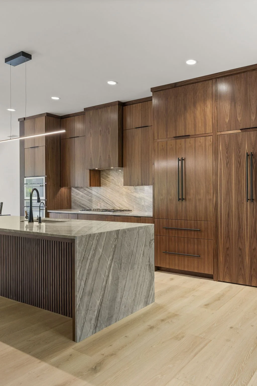 Modern kitchen remodel in Central Texas with walnut cabinetry and quartzite countertops by Atria Design + Build.