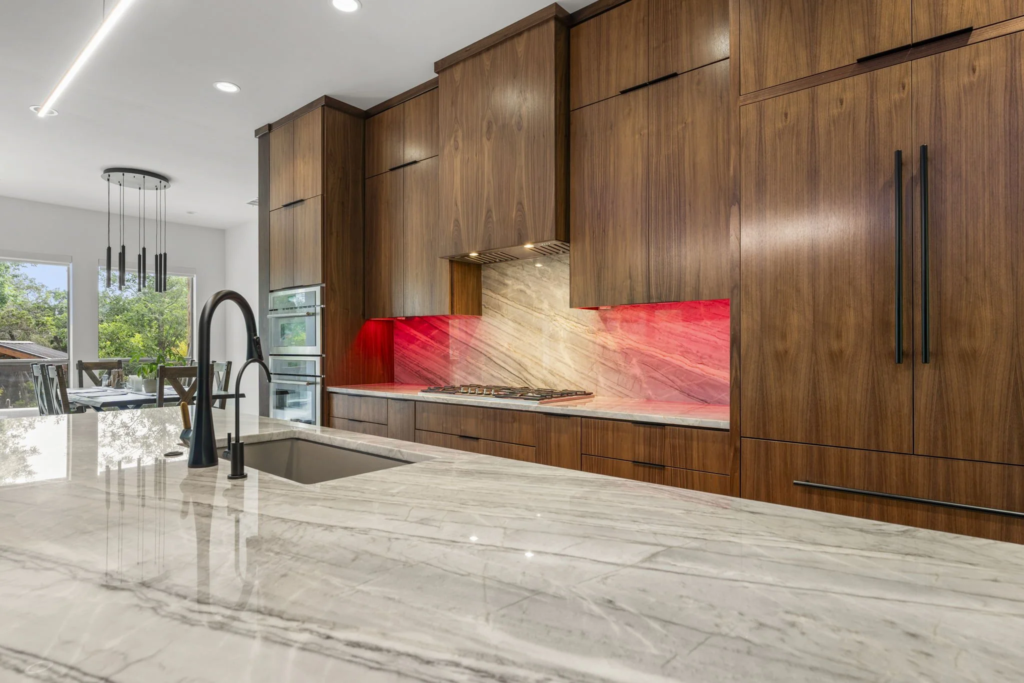 Modern kitchen remodel in Central Texas with walnut cabinetry and quartzite countertops by Atria Design + Build.”