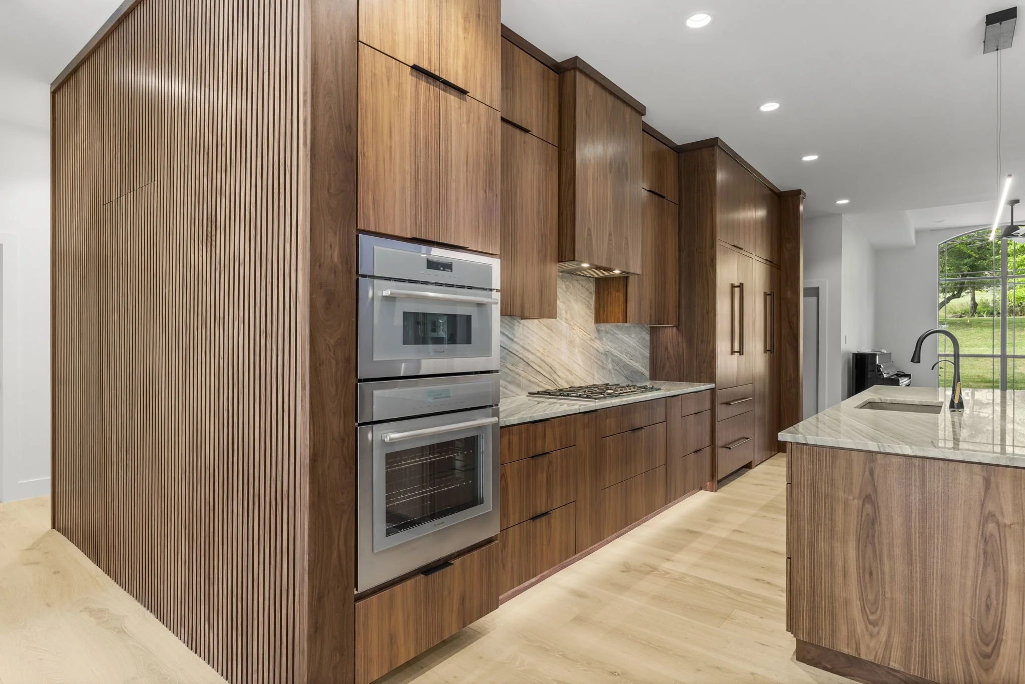 Modern kitchen remodel in Central Texas with walnut cabinetry and quartzite countertops by Atria Design + Build.”
