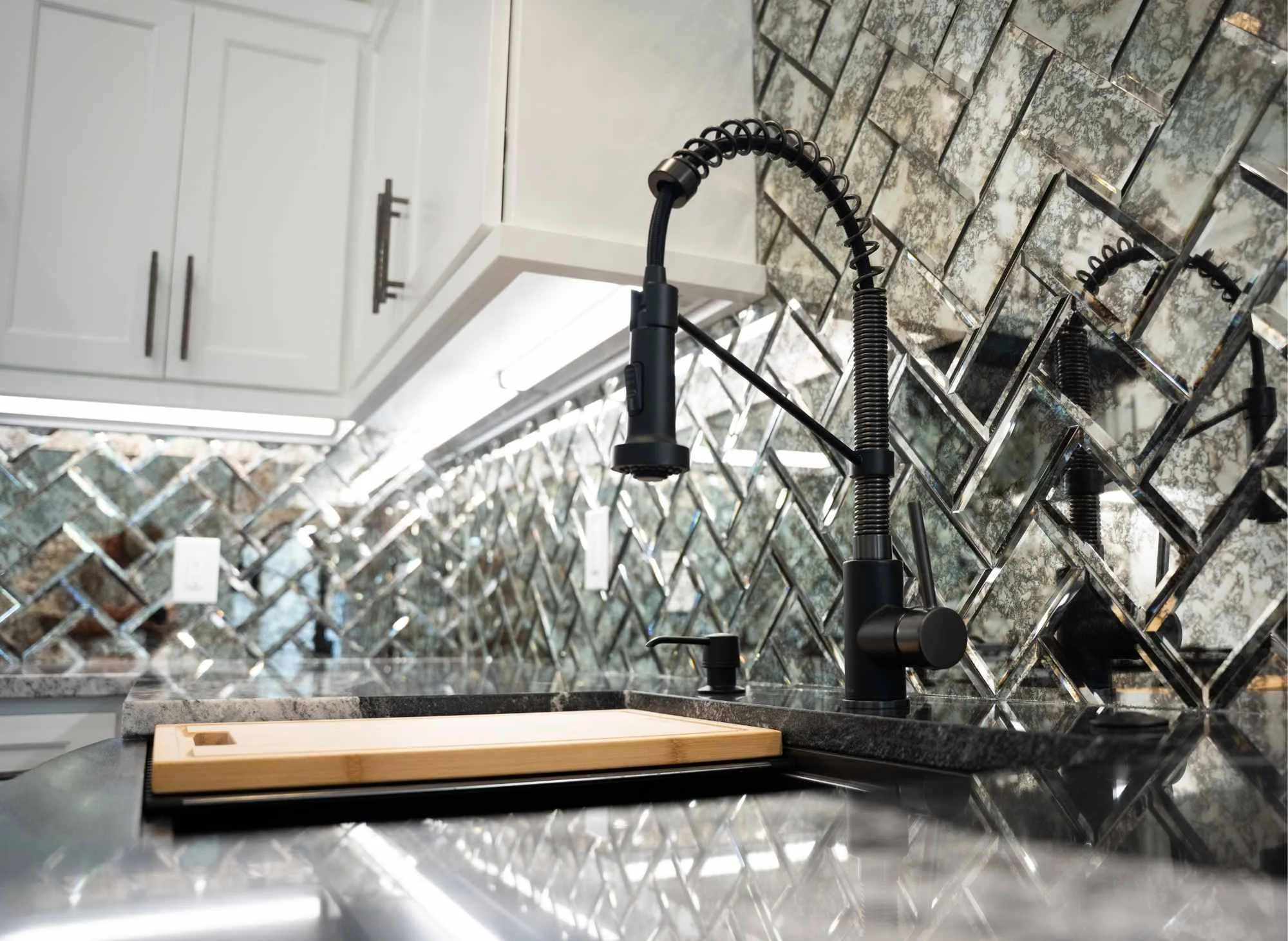 Casita kitchen with Marble countertops, mirrored backsplash, hardwood floors and black gunmetal appliances