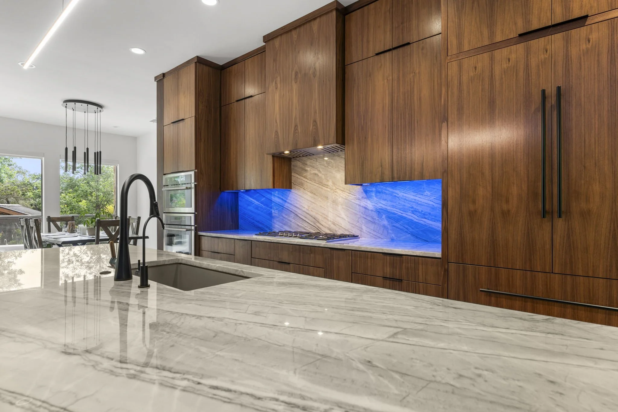 Modern kitchen remodel in Central Texas with walnut cabinetry and quartzite countertops by Atria Design + Build.”