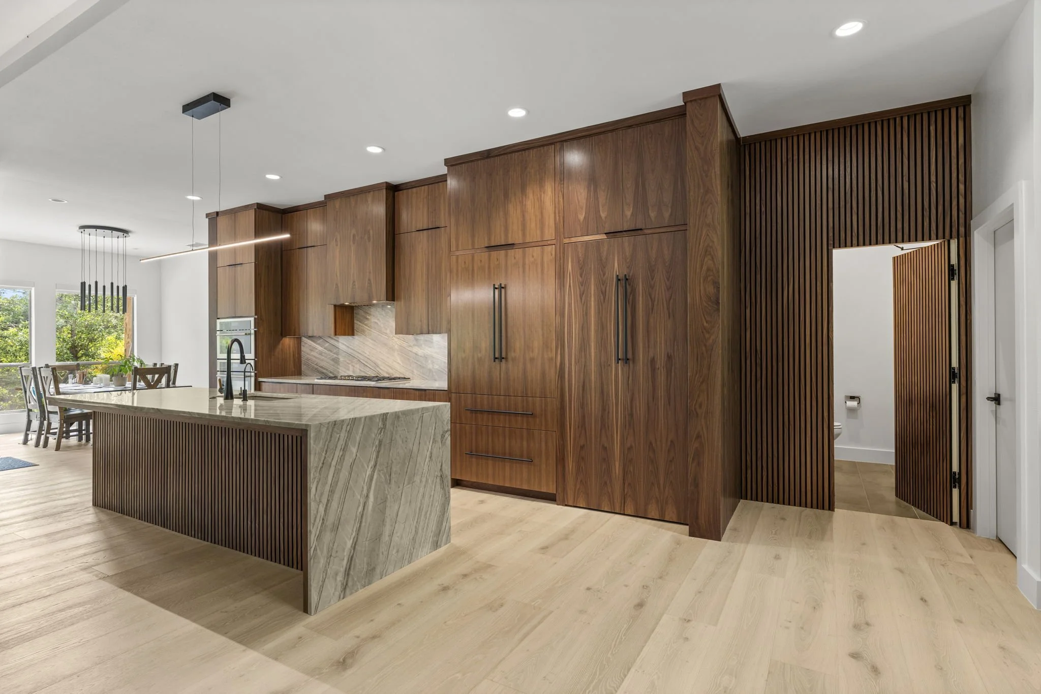 Modern kitchen remodel in Central Texas with walnut cabinetry and quartzite countertops by Atria Design + Build.”
