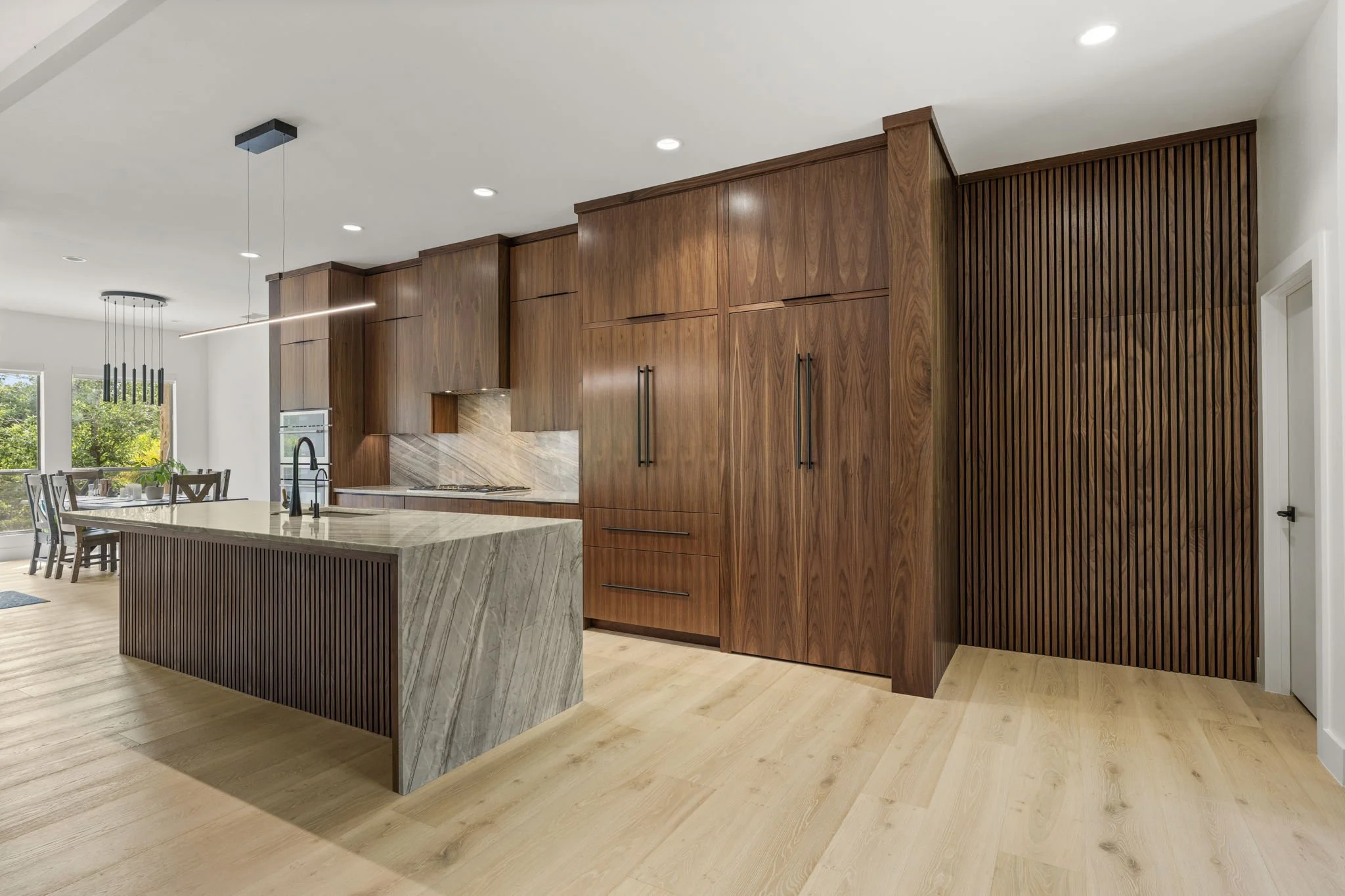 Modern kitchen remodel in Central Texas with walnut cabinetry and quartzite countertops by Atria Design + Build.”