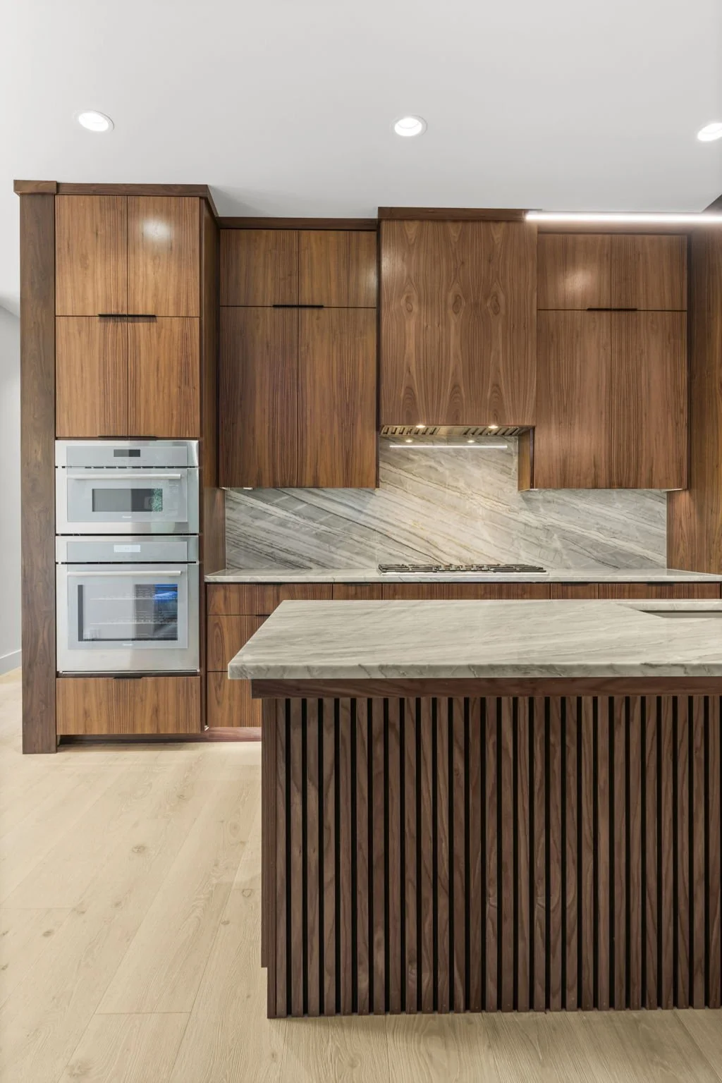 Modern kitchen remodel in Central Texas with walnut cabinetry and quartzite countertops by Atria Design + Build.