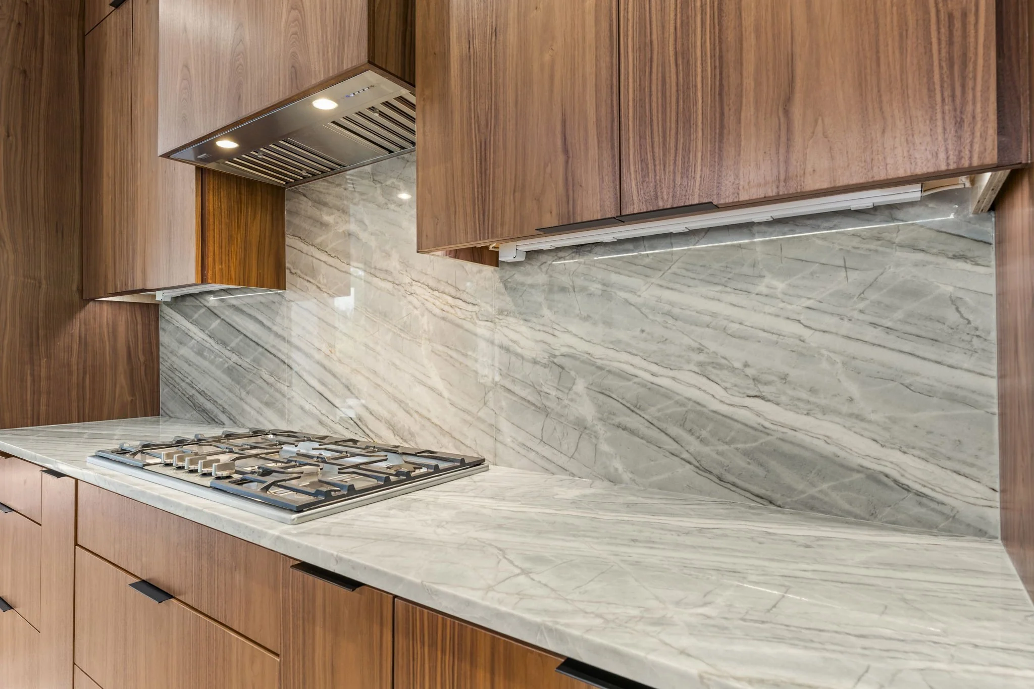 Modern kitchen remodel in Central Texas with walnut cabinetry and quartzite countertops by Atria Design + Build.”