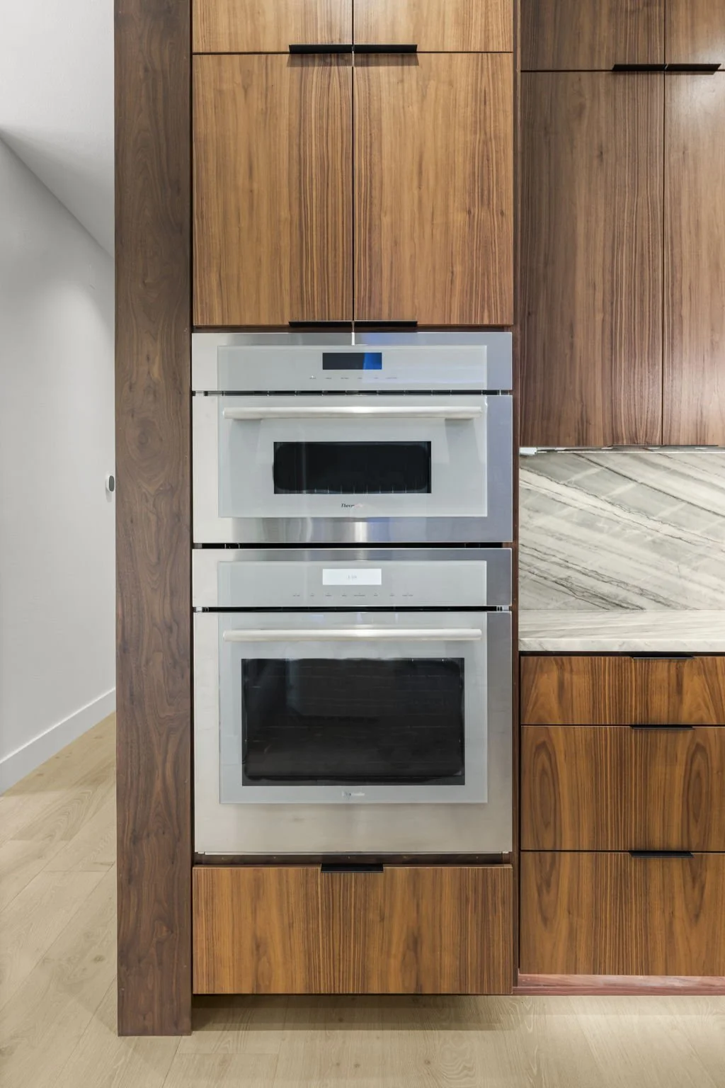 Modern kitchen remodel in Central Texas with walnut cabinetry and quartzite countertops by Atria Design + Build.