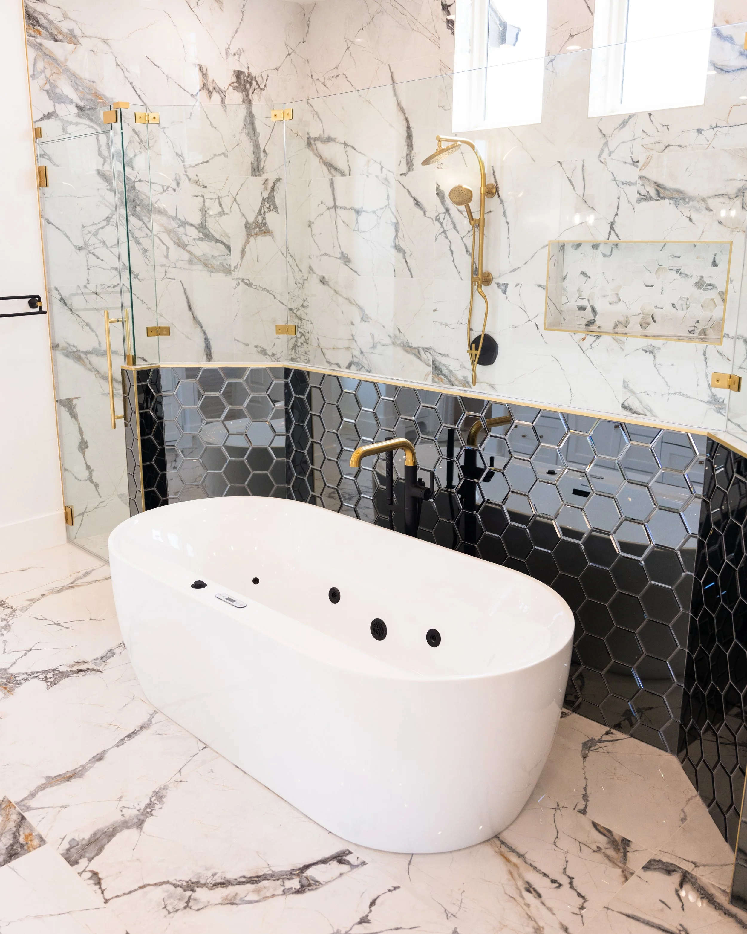 Custom home primary bathroom with floor to ceiling tile, jetted soaker tub, double shower. Central Texas