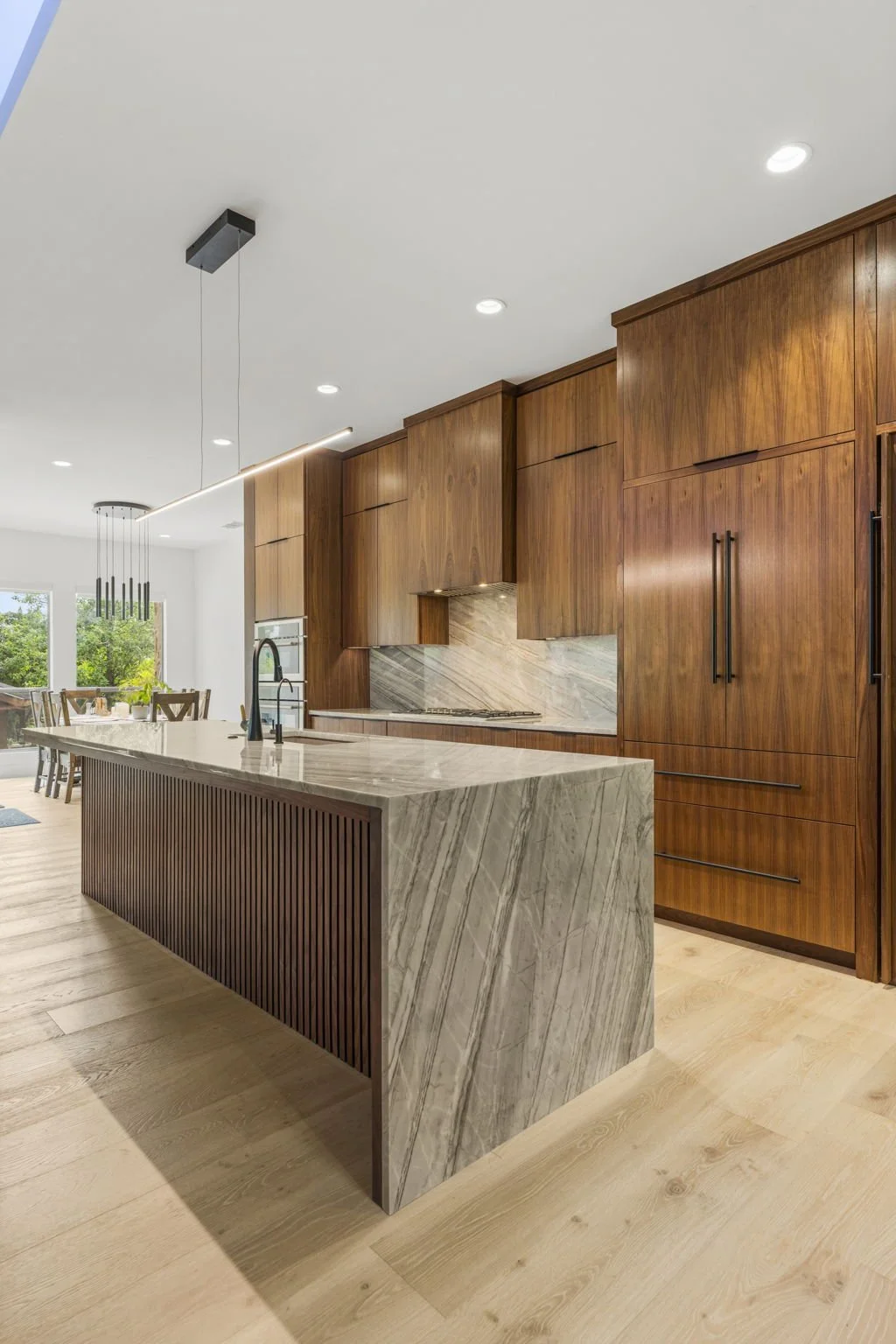 Modern kitchen remodel in Central Texas with walnut cabinetry and quartzite countertops by Atria Design + Build.