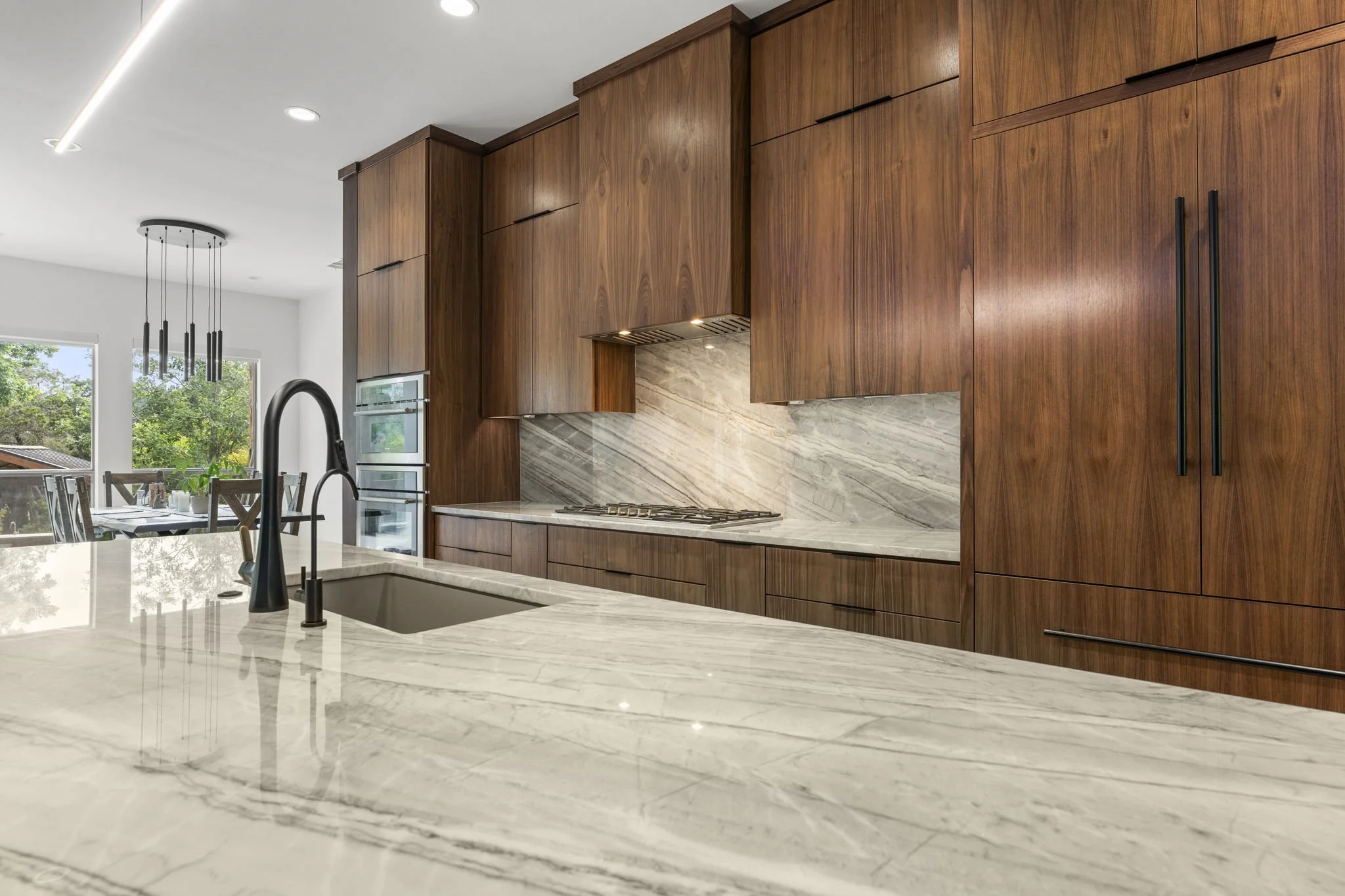Modern kitchen remodel in Central Texas with walnut cabinetry and quartzite countertops by Atria Design + Build.”
