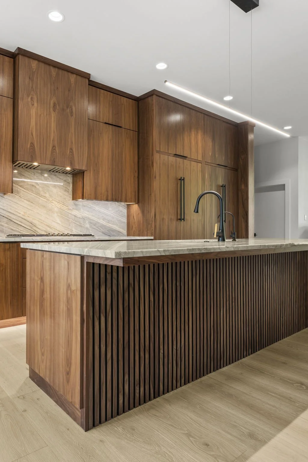 Modern kitchen remodel in Central Texas with walnut cabinetry and quartzite countertops by Atria Design + Build.