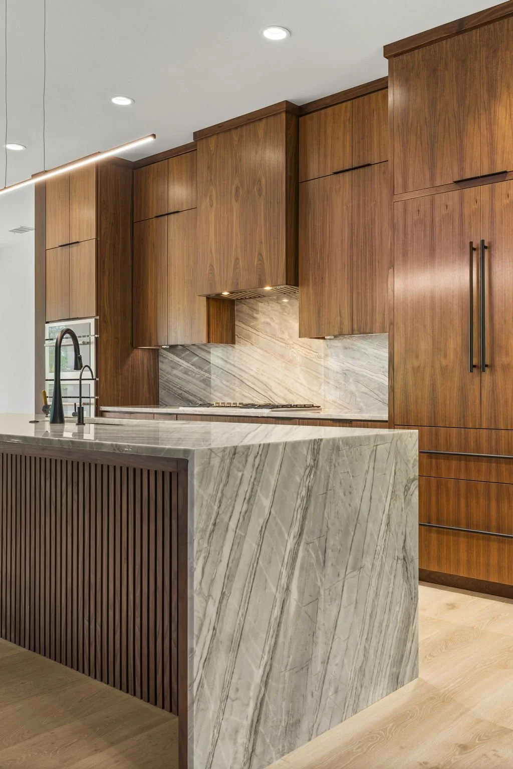 Modern kitchen remodel in Central Texas with walnut cabinetry and quartzite countertops by Atria Design + Build.”