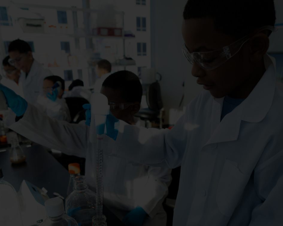 Scientists working in a laboratory with glassware and lab equipment, all wearing lab coats and safety goggles.