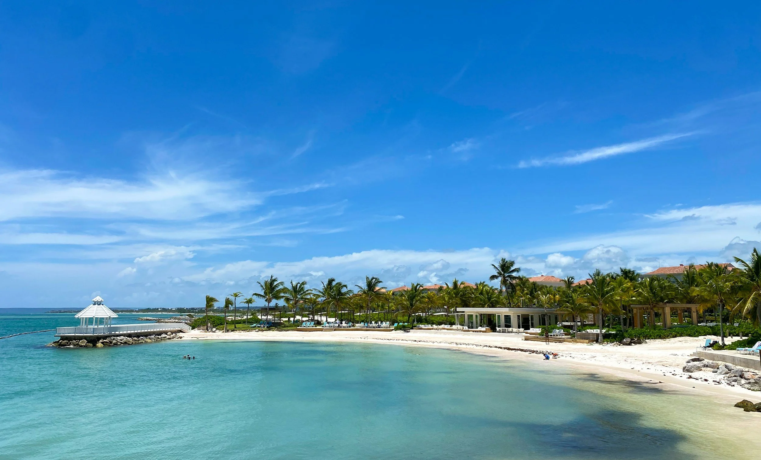 Tropical beach with turquoise water, white sand, palm trees, and a small white gazebo on a jetty under a blue sky with scattered clouds. - Client reviews for Travel with Sabeen luxury travel advisory in Louisville Kentucky