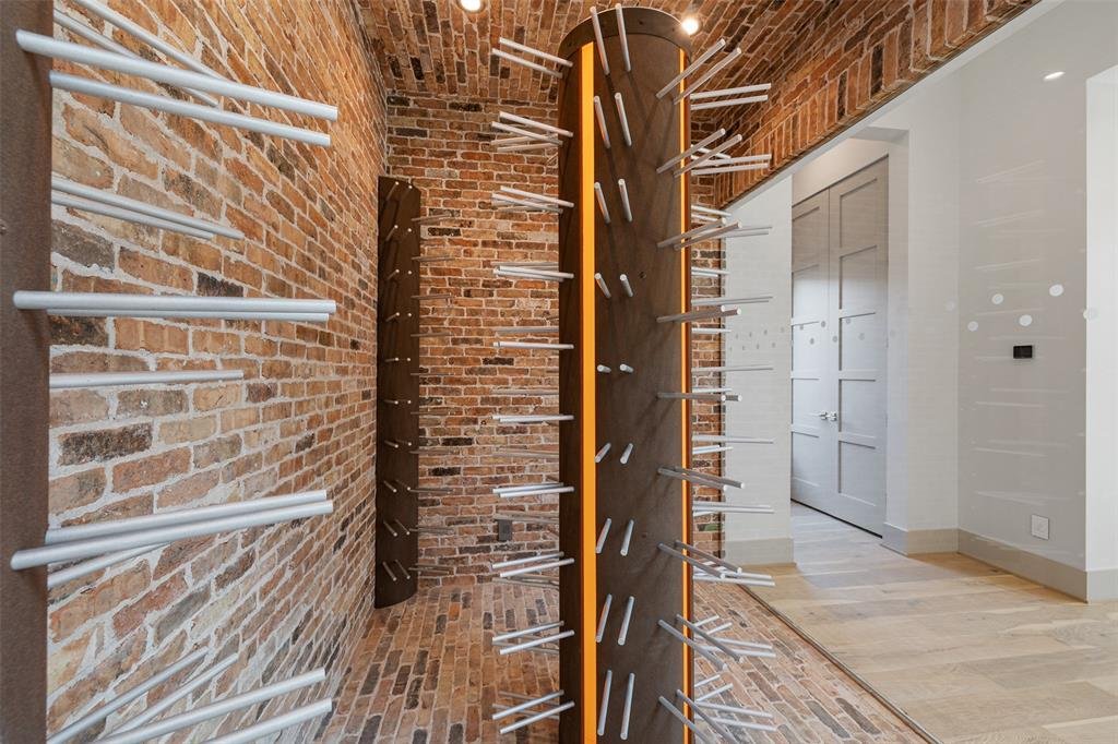 Interior of a room with brick walls, displaying vertical wall-mounted racks with rods, possibly for storing or displaying skis or similar equipment.