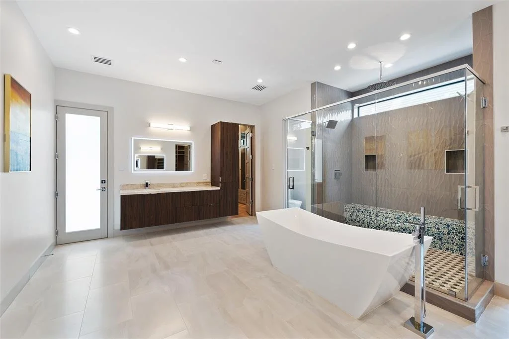 Modern bathroom with free-standing bathtub, glass-enclosed shower, vanity with mirror, and wooden cabinets.
