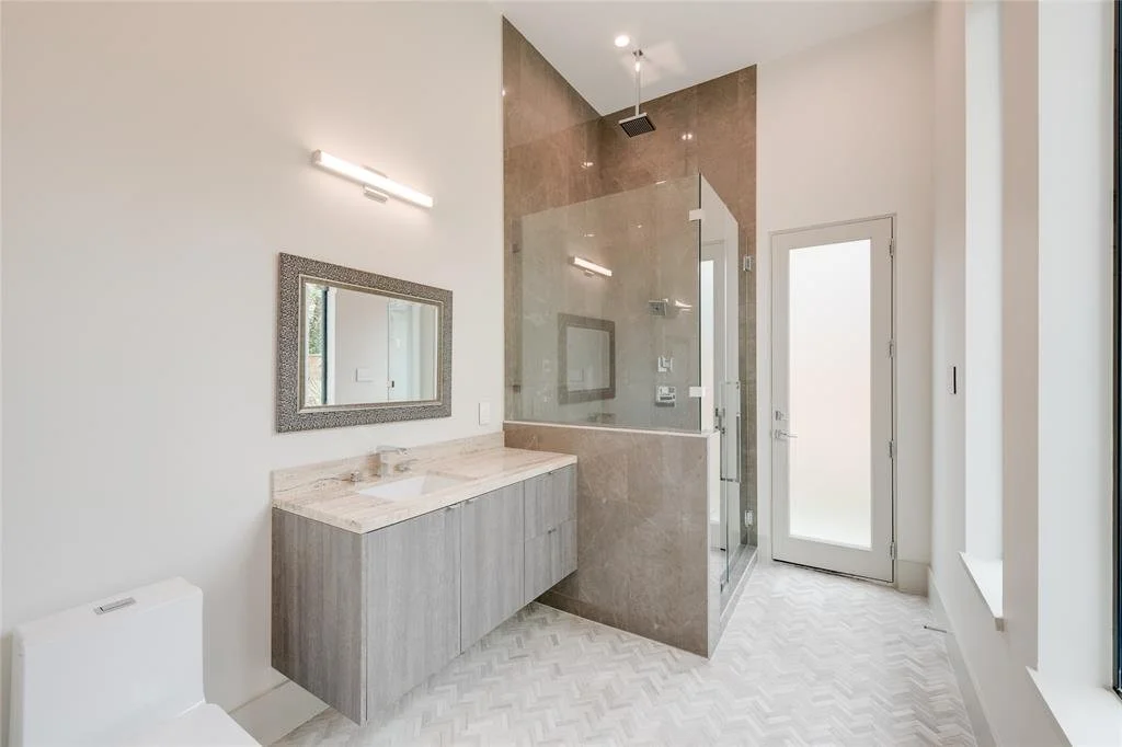 Modern bathroom with glass shower enclosure, a floating vanity with a marble countertop, a mirror, and a frosted glass door.