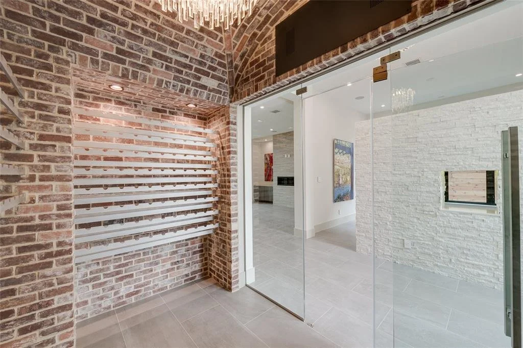 Interior view of a modern home with exposed brick walls, glass sliding doors, and white textured brick walls, featuring a small window and artwork on the walls.