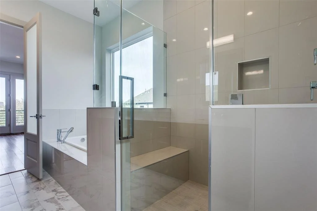 Modern bathroom featuring a glass-enclosed shower, a built-in bathtub, and a window with natural light.